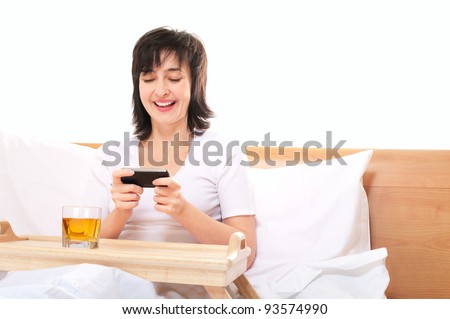 Woman plays video games on mobile smartphone in bed in bed isolated on white