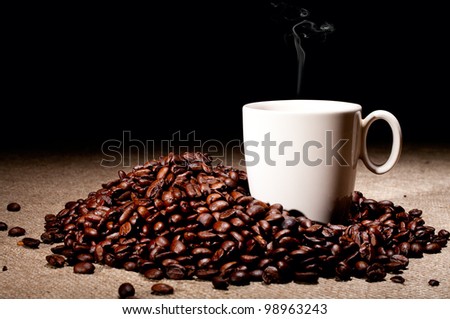 Coffee beans and cup with steam on jute