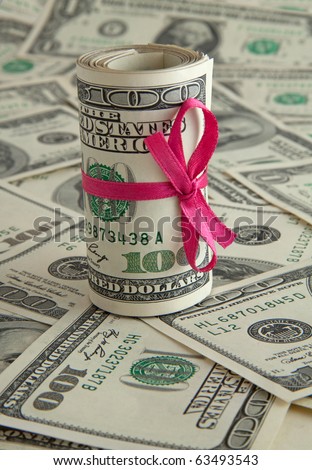 Holiday gift of money. 100 dollar bills with pink satin ribbon.
