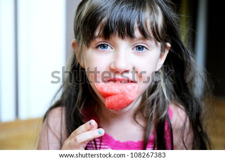 Cute little girl with a piece of watermelon in her mouth