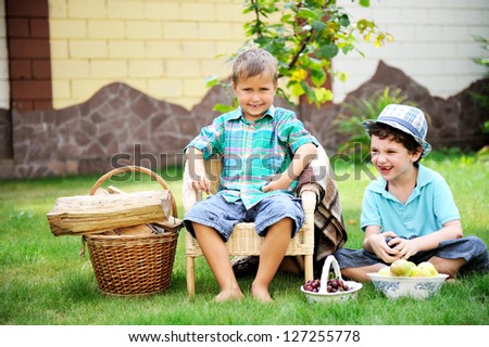 Two happy boys having picnic on a green lawn