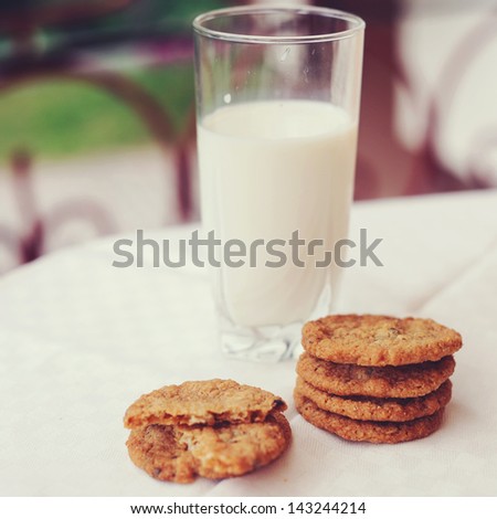 Square tone photo of glass of milk with cookies on the outdoor table