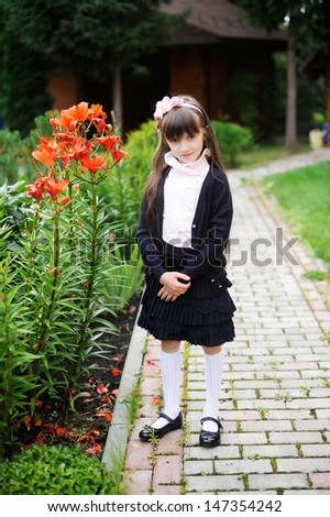Adorable school girl in navy elegant uniform outdoors