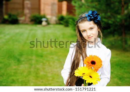 Young girl in school uniform posing with yellow and orange flower