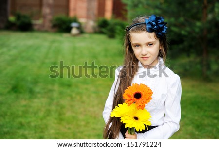 Young girl in school uniform posing with yellow and orange flower