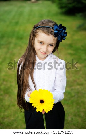 Young girl in school uniform posing with yellow flower