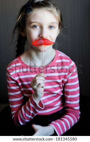 Beautiful little girl with mustache-shaped lollipop