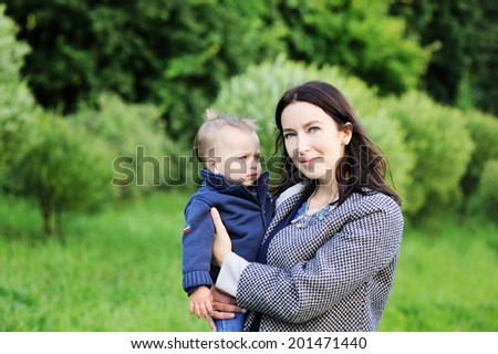 Young beauty  mother hugs her cute baby son outdoors in the park