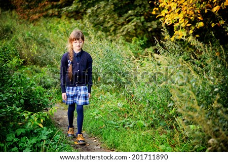 School girl in navy blue uniform has fun in the autumn forest after school