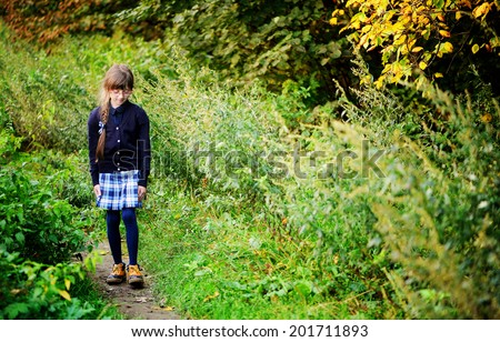 School girl in navy blue uniform has fun in the autumn forest after school