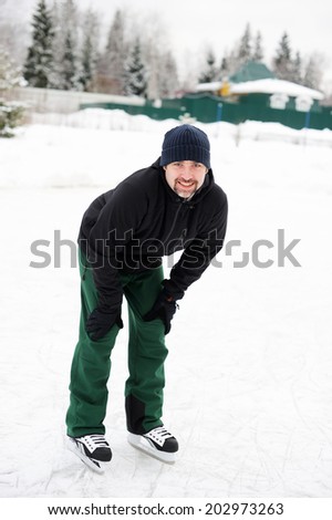 Active  handsome young man skating outdoors on the pond  in the country in winter cloudy day