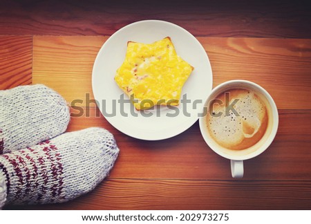 Morning coffee with cheese toast on the wood flor near the feet in cozy knit socks