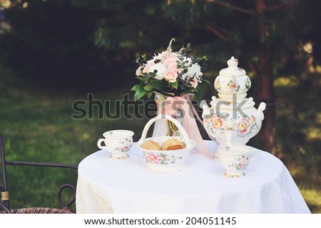 Tea table for two outdoor in the garden with elegant country style tableware: retro style toned