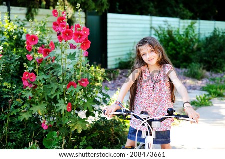 Adorable kid girl on her bike outside in the warm summer evening