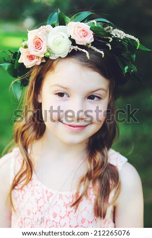 Portrait of adorable kid girl with flower wreath outdoor in the garden