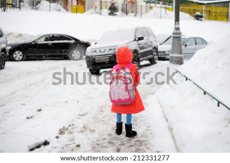 Adorable little girl walking from school on winter day in the city