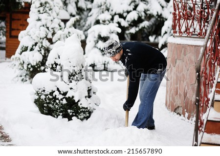 Handsome young man shoveling snow in the yard