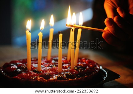 anniversary cake with hand  burning candles in dark