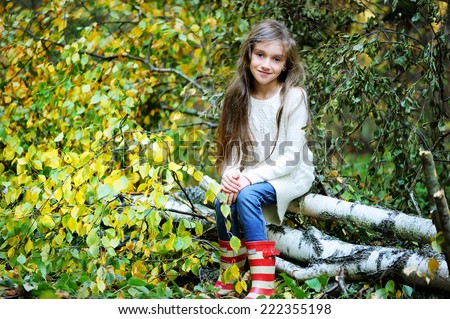 Beauty school aged brunette girl in white sweater and rain boots in the beauty autumn forest