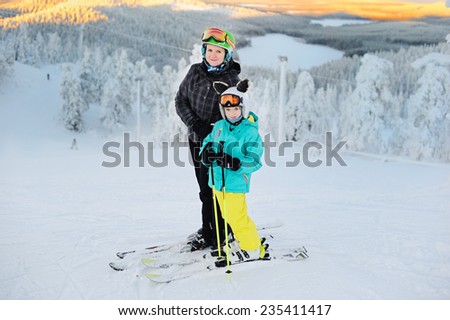 Happy smiling girl  and with her mother in ski goggles and helmets on the top of the hill with beauty view of Ruka. finland