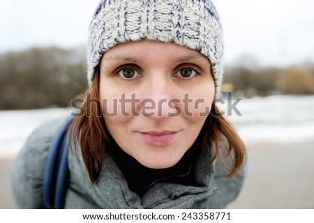 Happy young woman in grey coat and hat enjoying early spring walk in the park