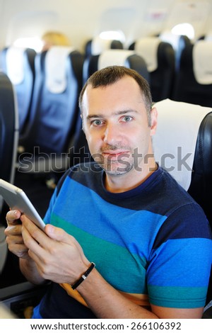 Handsome man with tablet in airplane on his way to vacation