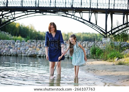 Family portrait of a smiling and cheerful mother and daughter having fun near th river