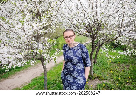 Beautiful black hair woman in glasses enjoying blooming tree , pretty woman relaxing outdoor. Happy young lady and spring green nature.  Gardens.