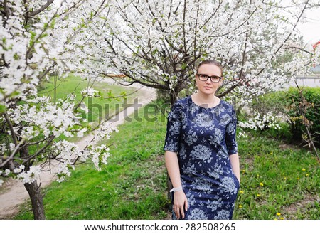 Beautiful black hair woman in glasses enjoying blooming tree , pretty woman relaxing outdoor. Happy young lady and spring green nature.  Gardens.