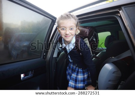 Beauty school aged kid girl in glasses and uniform near the car