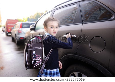 Beauty school aged kid girl in glasses and uniform near the car