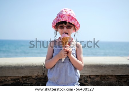 Small girl in glasses and sun hat on sea background with ice cream