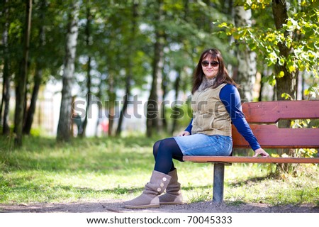 Portrait of nice brunette  middle age woman  with sun glasses in the park
