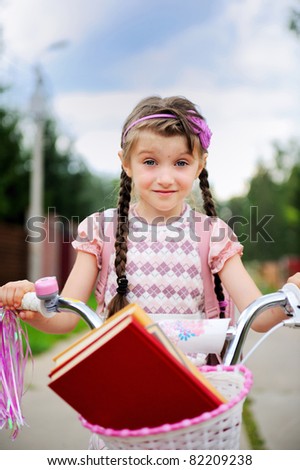 Young school girl rides her pink bike to school