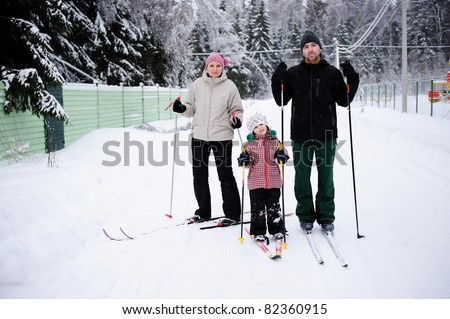 Young happy family enjoy skiing in rural area on winter day