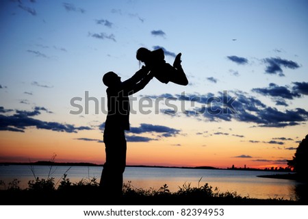 Silhouette of a father lifting up his daughter in the sunset