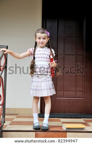 Young school girl with pink backpack waits on stairs