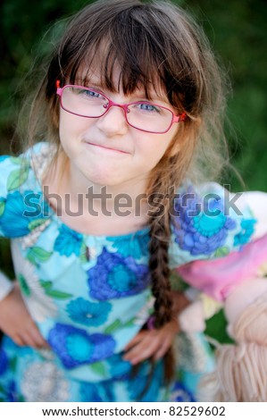 Adorable child girl in glasses makes a funny angry face, with focus on face