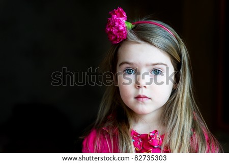 Portrait of adorable child girl with flower headband on a dark background