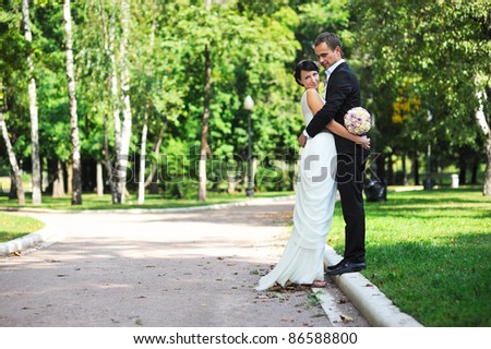 Bride and groom hugging each other gently during a walk in the summer park