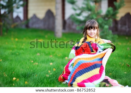 Portrait of cute child girl sitting with a rose and toys outdoors