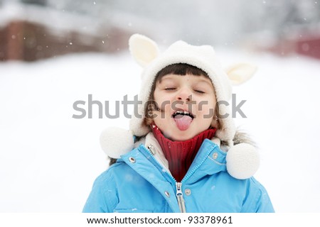 Cute toddler girl in snowsuit posing outdoors on bright winter day