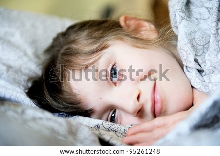 Smiling child girl lying in the bed in early morning