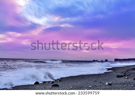 Surf on the black beach with black sand at pink sunset  background. South of Iceland.