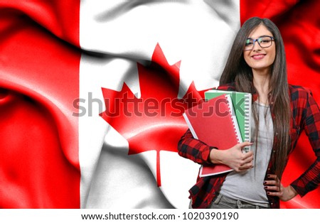 Happy female student holdimg books against national flag of Canada