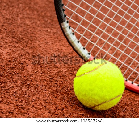 Tennis ball and racquet on a tennis clay court