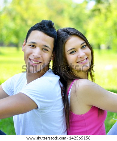 Happy young couple back to back in park
