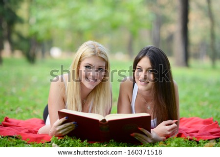Two girls reading book in park
