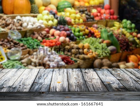 Background With Empty Wooden Table And Blured Fruits And Vegetables