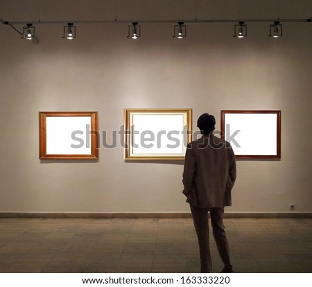 Man In Gallery Room Looking At Empty Picture Frames